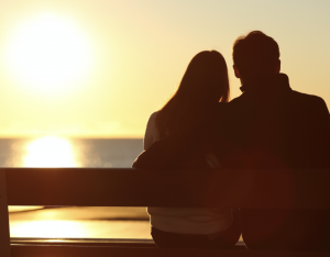 young couple sitting on bench enjoying sunset