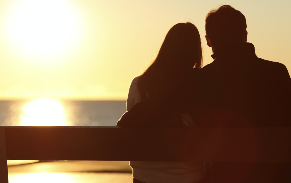 young couple sitting on bench enjoying sunset